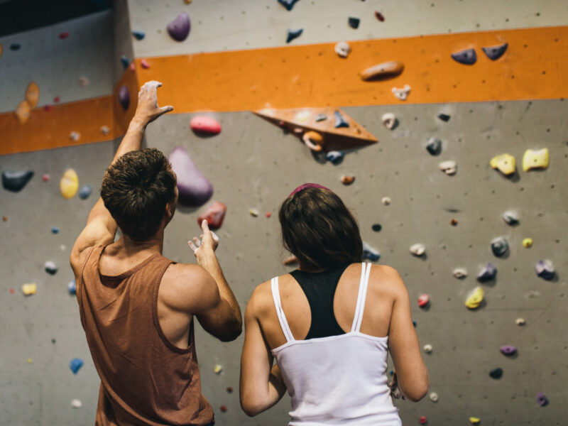 photo of man and woman standing in front of climbing wall